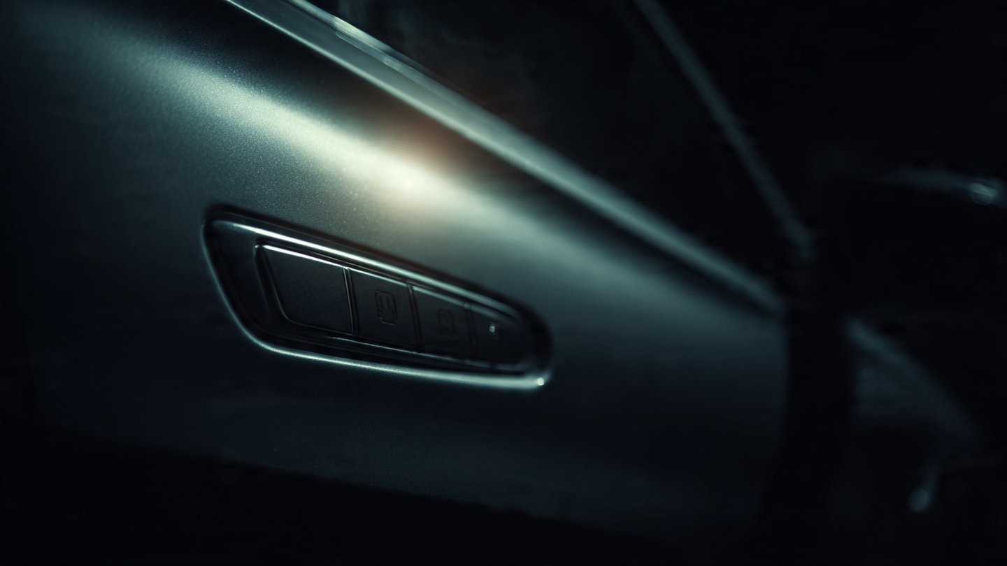 A flush electronic door handle on a modern car, with a faint emergency release label barely visible in shadow