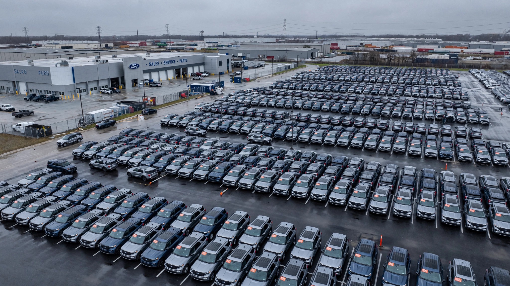 Rows of Ford Explorers lined up at a dealership lot under overcast sky