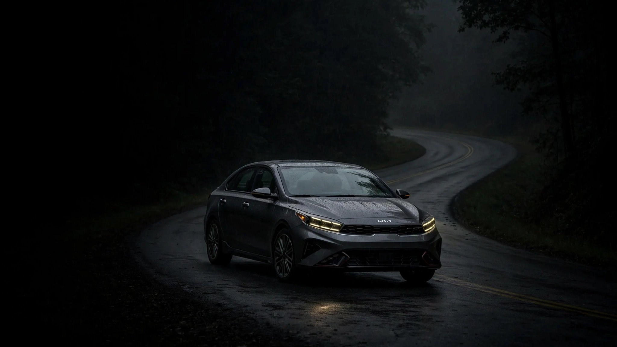 A Kia Forte sedan driving at night with dim halogen headlights