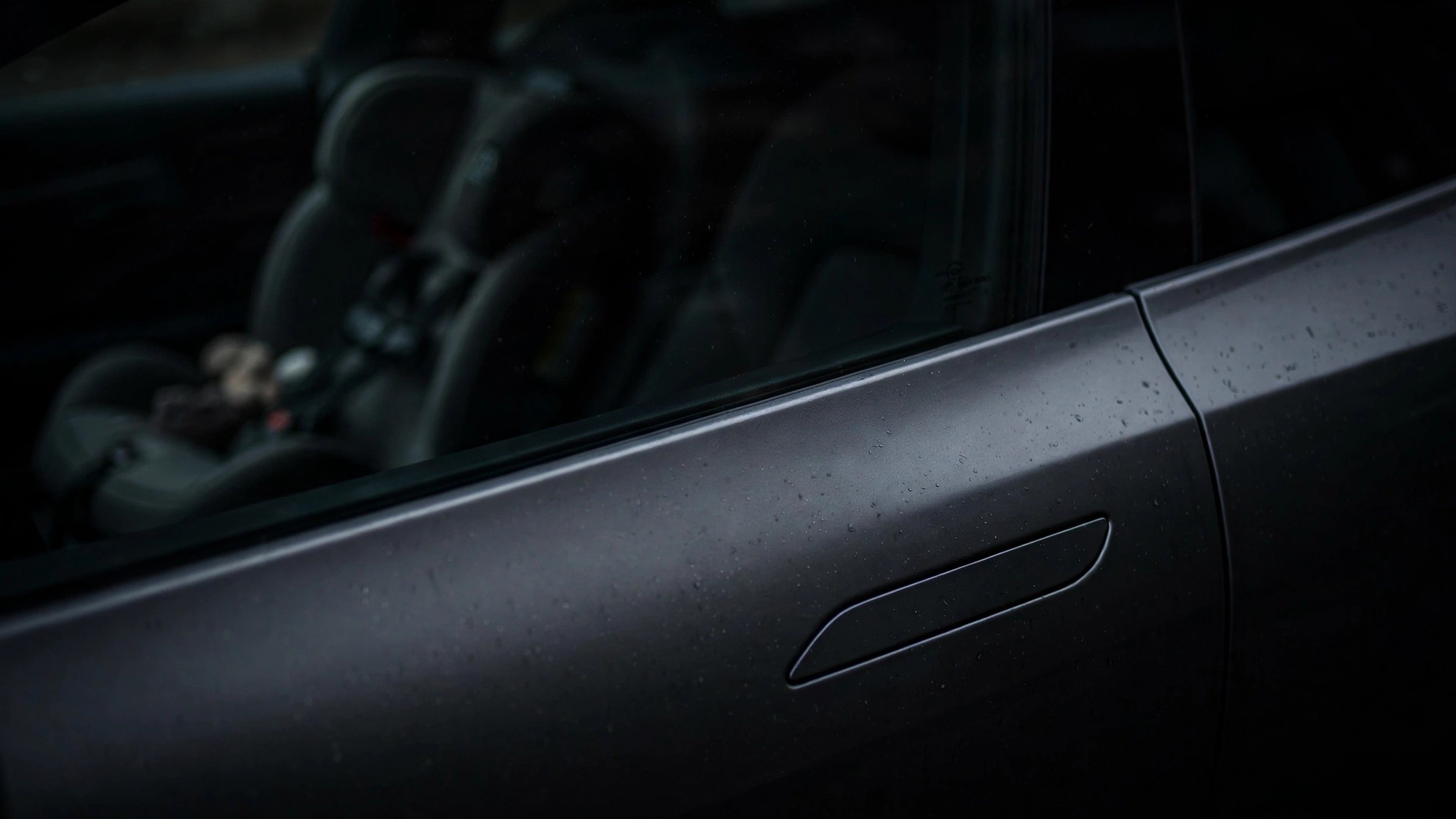A flush electronic door handle nearly invisible on a dark car body panel