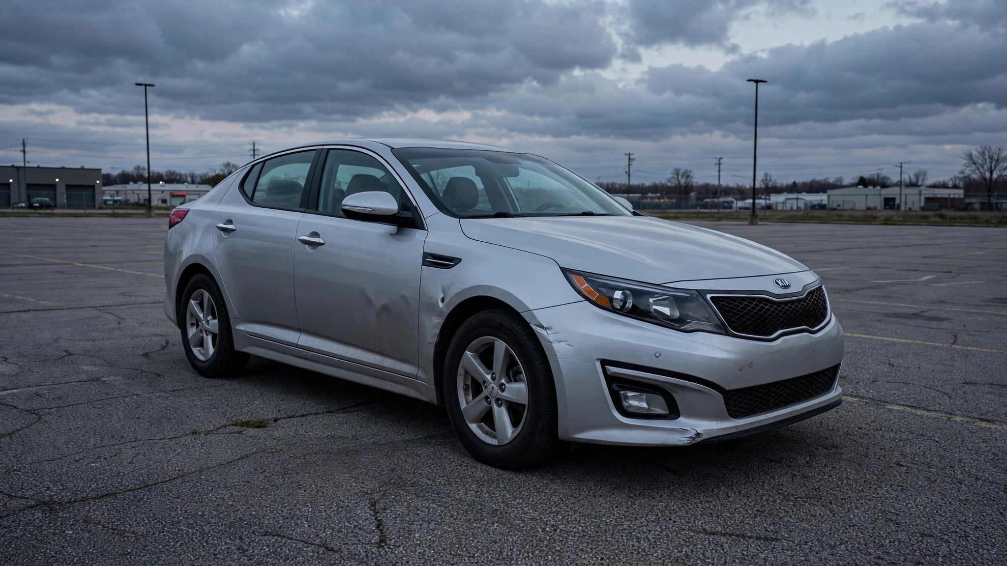 A silver Kia Optima sedan sitting alone in an empty parking lot