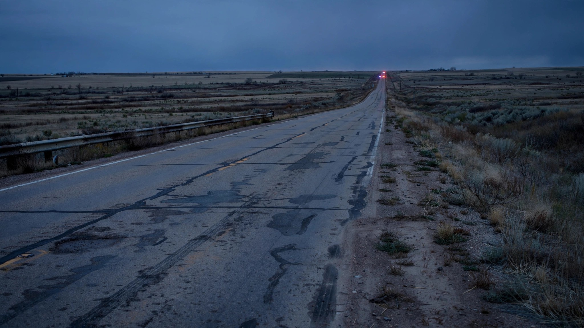 A desolate rural interstate highway stretching into the horizon at dusk