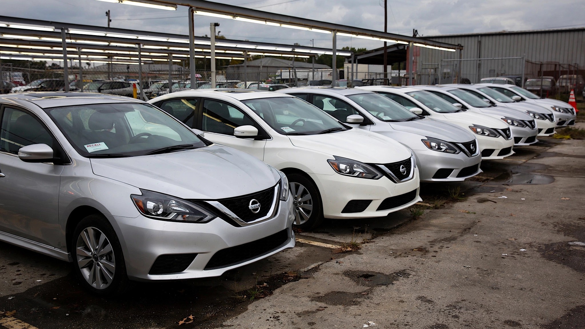 Row of aging Nissan Sentras in a dealership lot