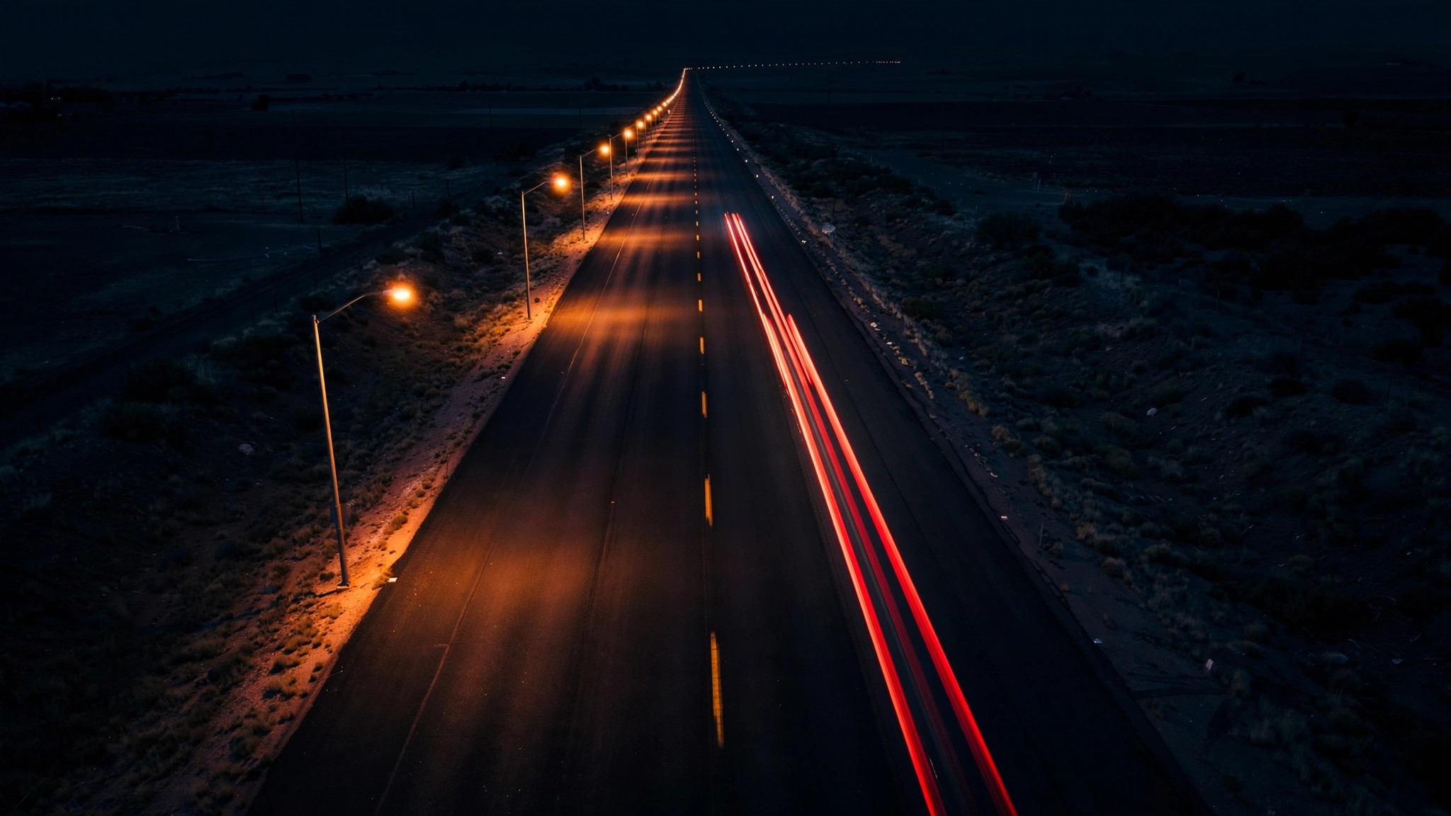 Empty highway at night with blurred red taillights from a speeding car