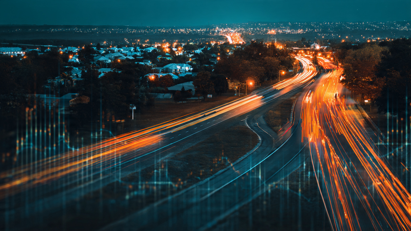 Aerial view of American highway at dusk with long exposure light trails and a flatlined graph at 36,000