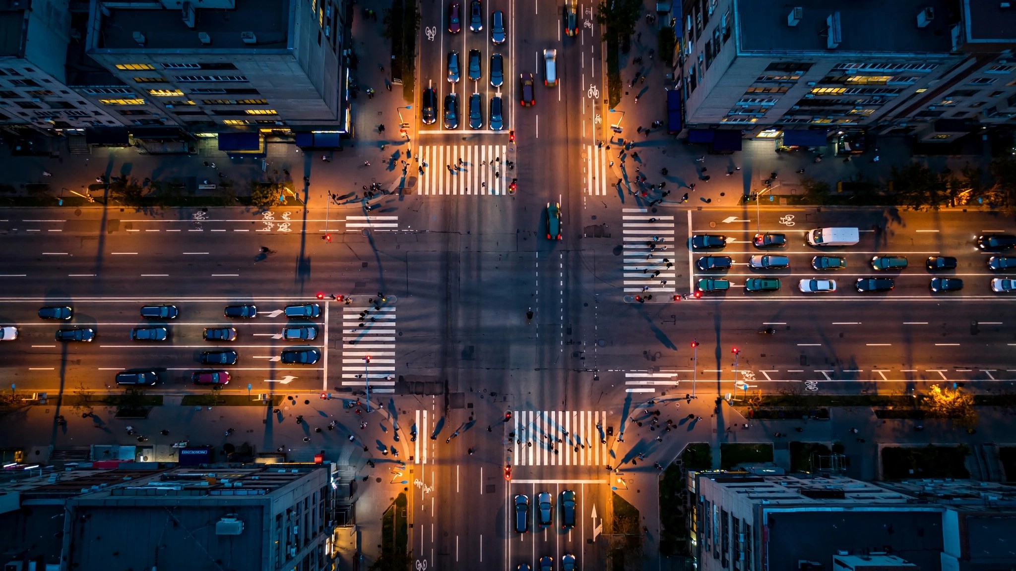 Aerial view of a dense urban intersection at night with converging crosswalks